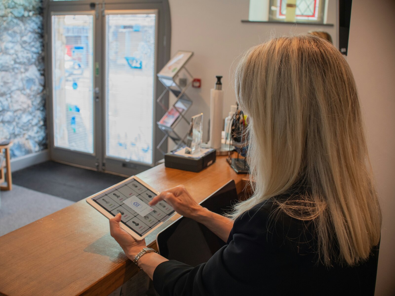 A practice manager reviewing a booking system on a tablet at reception